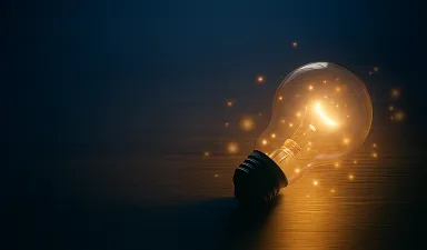 A glowing light bulb on a dark wooden surface